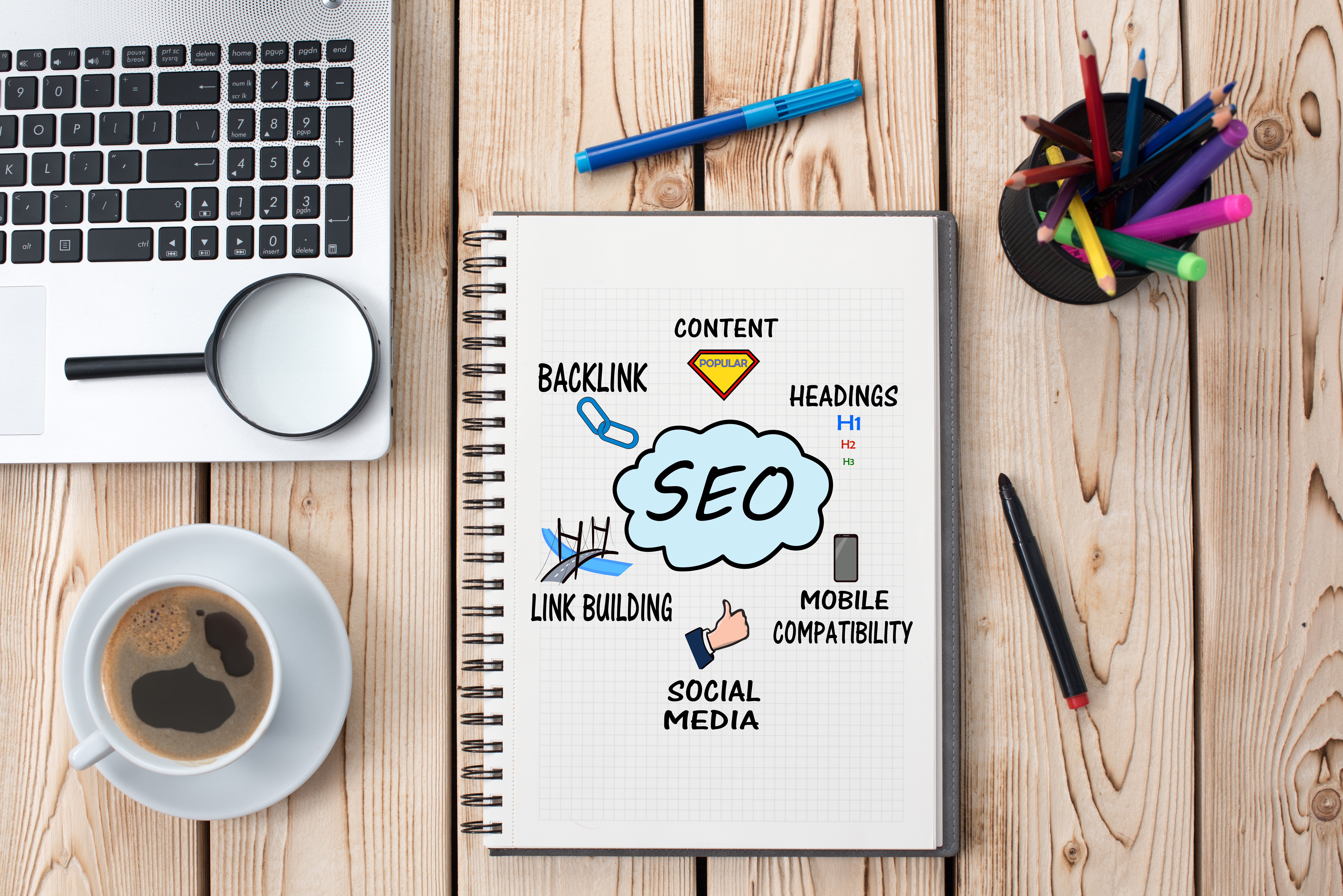 A SEO notebook with pencils, coffee, and laptop ready for a meeting